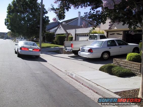 White sedan parked on street, white pickup truck and white sedan parked in driveway