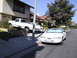 1997 Ford Thunderbird - A white sedan is parked on the street in front of a house, with a white pickup truck partially visible on the driveway.