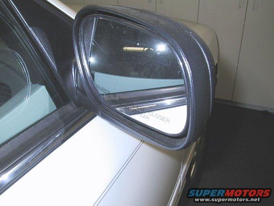 Side mirror on a white car with pinstripes. Text on mirror says 'Objects in mirror are closer than they appear'