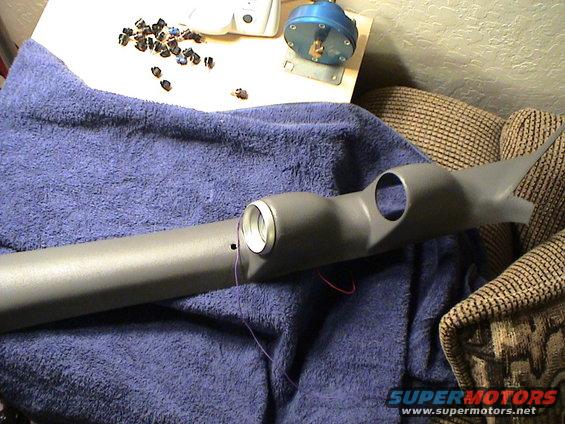 Gray plastic gauge pod with two openings, wires attached, on a blue towel