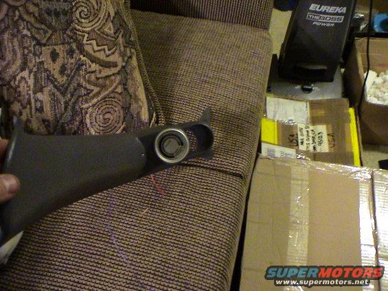 Hand holding a dark gray car interior trim piece with a circular opening