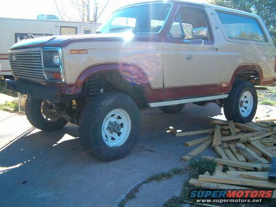 Tan and maroon Ford Bronco with aftermarket bumper and lifted suspension