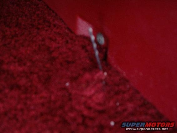 Red carpeted floor with a red metal panel and a bolt