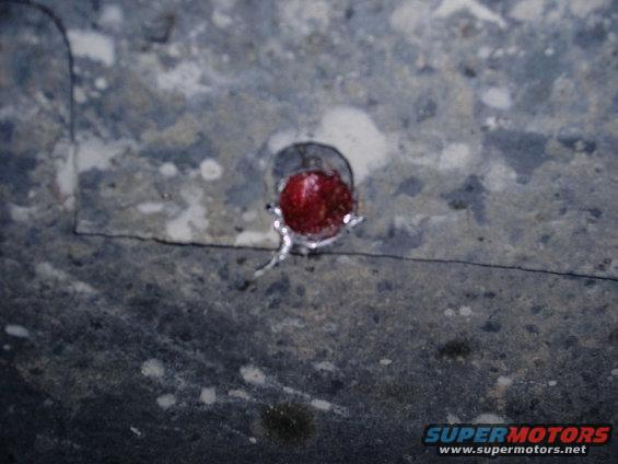 Red reflector on a gray, textured surface with a thin black line