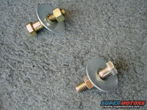Two bolts with washers and nuts on gray carpeted surface
