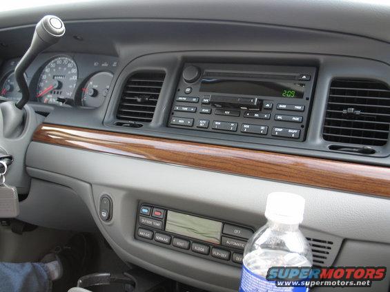 2003 Ford Crown Victoria interior dashboard with wood trim, radio, and climate controls. Water bottle on console