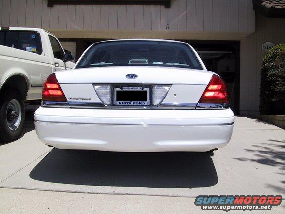 Rear view of a white 2003 Ford Crown Victoria parked next to a white pickup truck