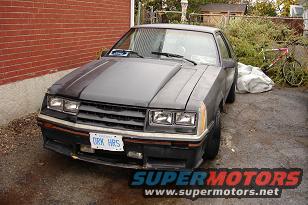 1981 Ford Mustang front view parked outside with a brick wall and bushes