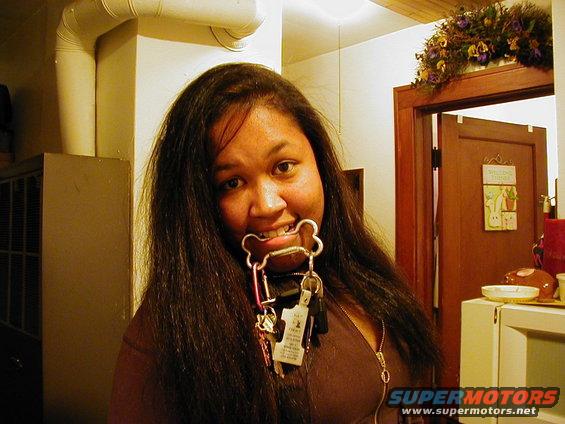 Woman holding a bone-shaped keychain with keys in her mouth, indoors