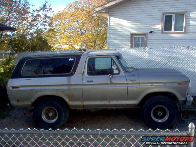 Silver 1978 Ford Bronco with black top, showing rust spots and a side view