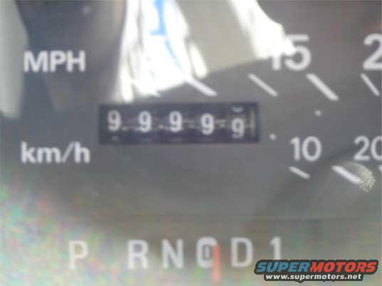 Close-up of a car's dashboard showing the odometer reading 99999 and the gear selector in Park