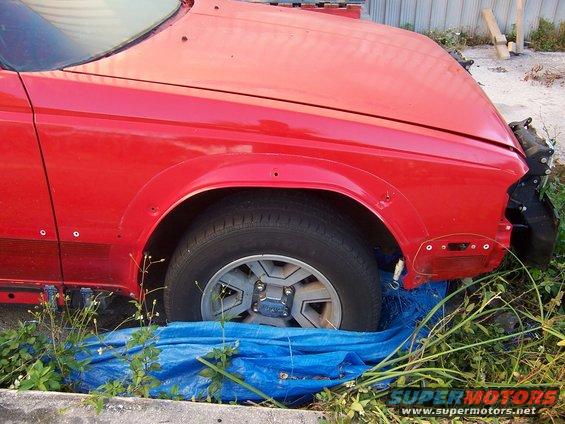 Red car fender and wheel, front view, showing damage and missing parts