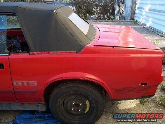 Red 1984 Toyota Celica GTS convertible, rear quarter view, soft top up, showing rust and damage