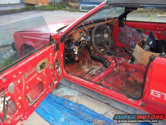 red convertible car with doors open, interior stripped bare, wires exposed