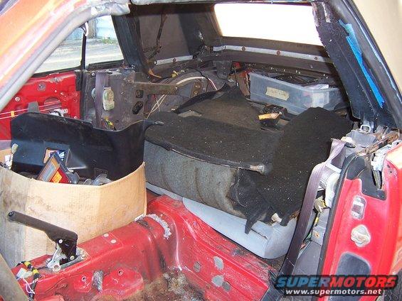 Interior of a red 1984 Toyota Celica with seats removed and parts scattered