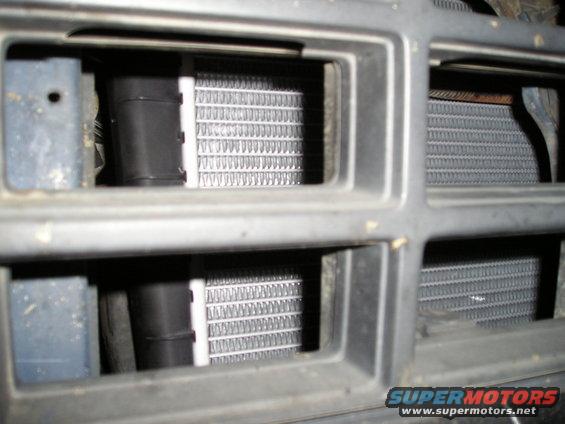 Radiator fins visible through a gray grille with black plastic components