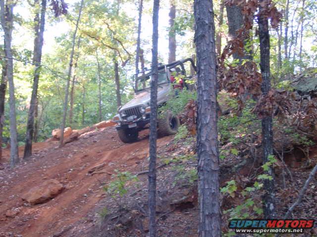Silver Jeep Wrangler TJ climbing a dirt hill