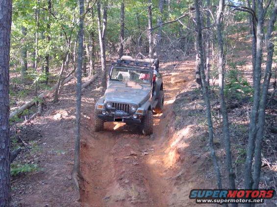 Jeep TJ driving up a dirt trail in the woods