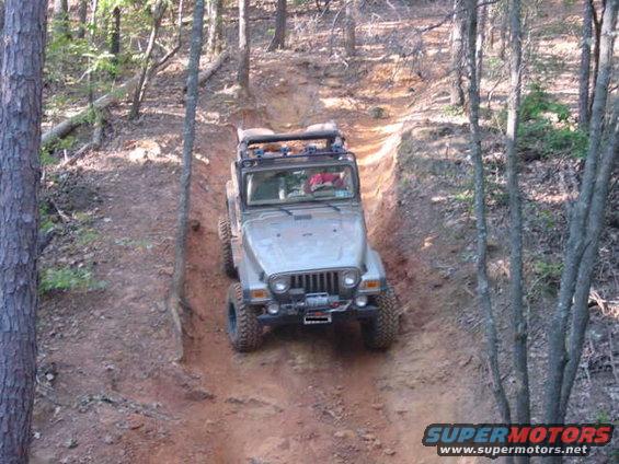 Silver Jeep Wrangler climbing a dirt hill, front winch visible
