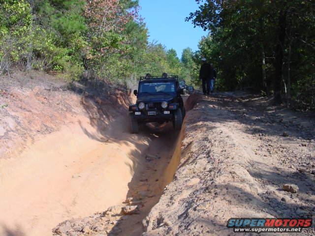 Black Jeep TJ driving on a dirt trail, front view