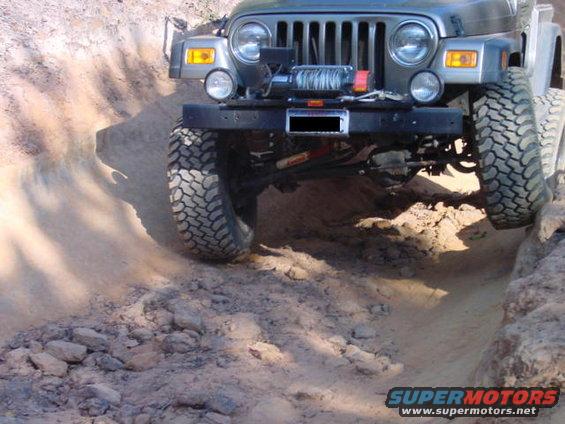 Gray Jeep Wrangler front bumper with winch, off-roading on a dirt path