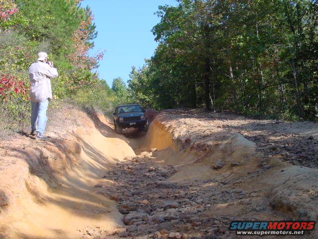 2004 Jeep TJ navigating a steep dirt trail with a photographer on the side