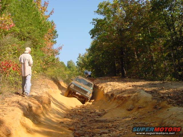 Jeep Cherokee XJ going down a steep dirt trail with a person watching