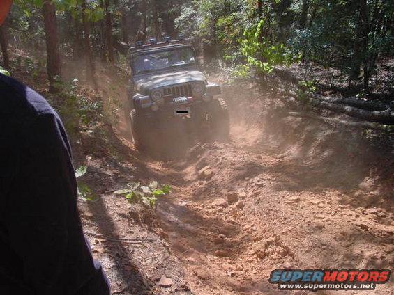 Green Jeep Wrangler TJ driving on a dirt trail