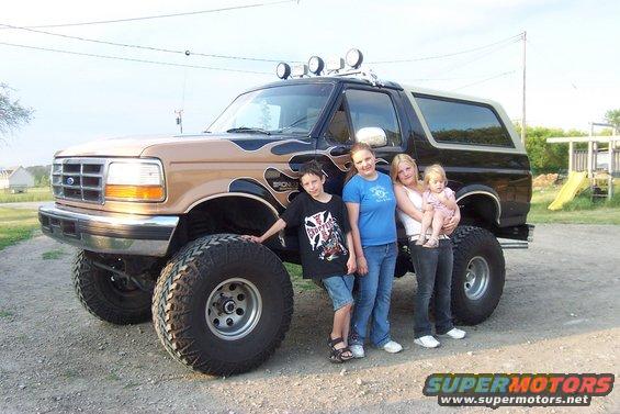 1995 Ford Bronco with flame decals and large tires, viewed from the front-three-quarter angle