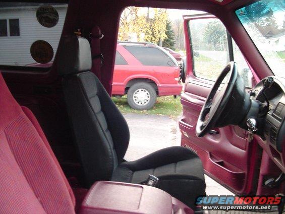 1994 Ford Bronco interior, showing front seats and dashboard; red SUV visible through open door