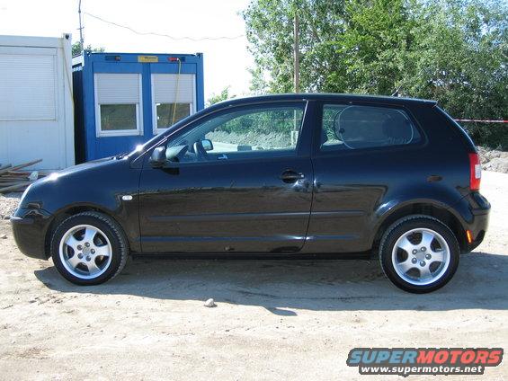 Black hatchback parked on dirt lot next to blue shipping container