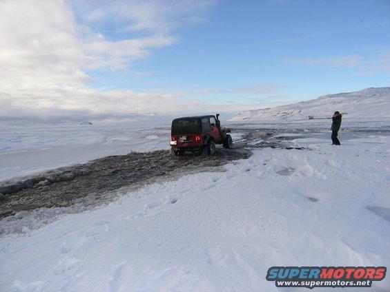 Red Jeep TJ driving on snow, rear view. 2001 model