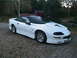 1996 Chevrolet Camaro - This white 1996 Chevrolet Camaro features a black convertible top and is shown from a 3/4 front angle.