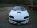 1996 Chevrolet Camaro - Front view of a white 1996 Chevrolet Camaro with a custom hood scoop, parked outdoors. A red pickup is in the background.