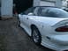 1996 Chevrolet Camaro - A white 1996 Chevrolet Camaro with a black t-top roof is parked outside a garage.