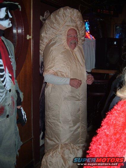 Man in a beige mushroom costume stands next to a skeleton figure in a bar