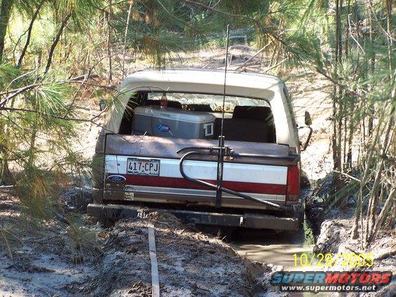 1987 Ford Bronco stuck in mud, rear view, brown and white exterior, license plate 417-CPJ