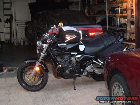 Black Suzuki motorcycle parked in garage next to a black car and a red car