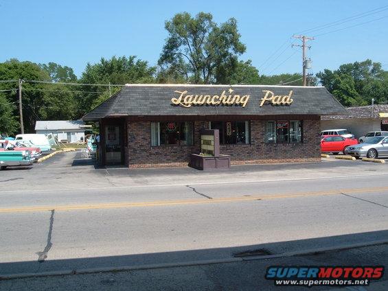 Launching Pad restaurant with several vintage cars parked outside