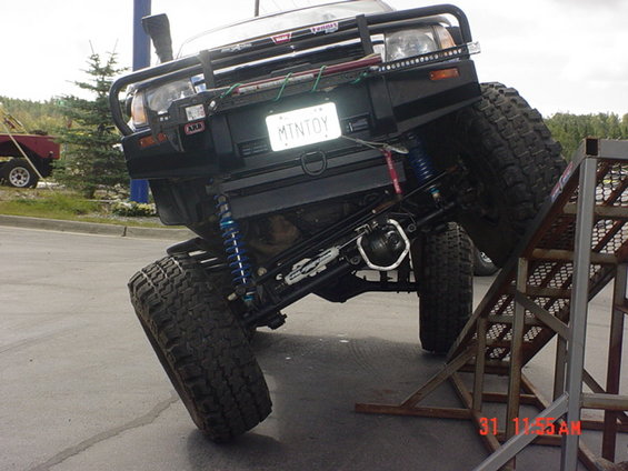 Black modified SUV with large tires and suspension, angled on a ramp