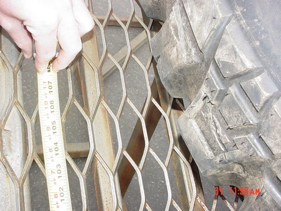 Measuring a tire tread with a tape measure against a metal grate. Time stamp reads 11:58 AM