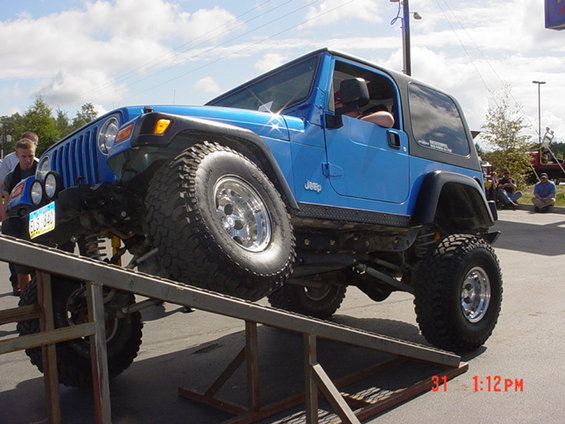 Blue Jeep Wrangler TJ with lifted suspension on a metal ramp