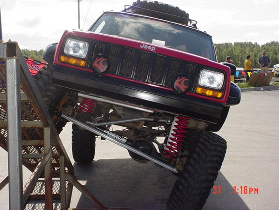 Red Jeep Cherokee XJ with off-road suspension on a metal ramp