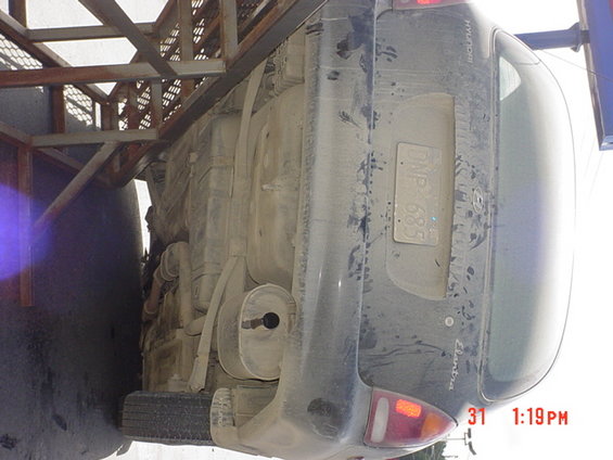 Dark sedan, rear view, upside down, covered in dust, license plate visible