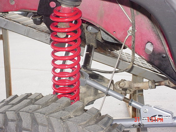 Close-up of a red coil spring and suspension components on a vehicle, with visible text 'ST 1:51PM'