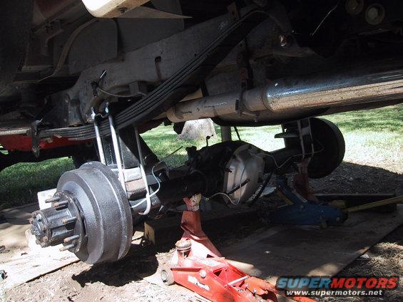 Rear axle, leaf springs, and brake drum assembly on a vehicle supported by jacks