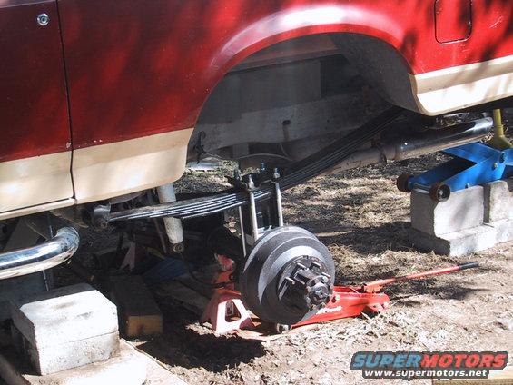 Rear leaf springs and brake drum on a red and tan 1990 Ford Bronco