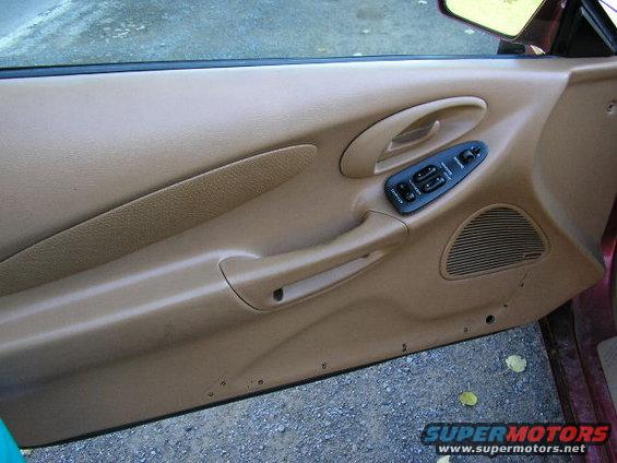 Interior of a car door panel with window controls and speaker grille
