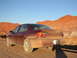 1979 Chevrolet Caprice - A maroon sedan is parked on a dirt road with red rock formations under a clear blue sky.