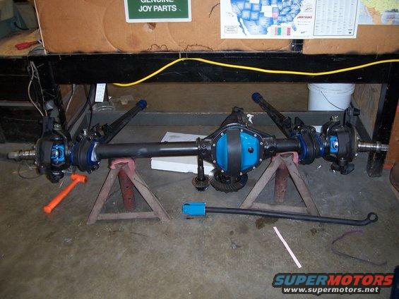 Front axle assembly on jack stands, with tools nearby